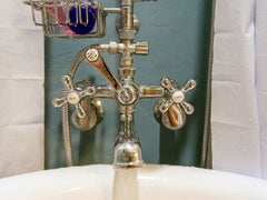 The faucet of a clawfoot tub against a light blue wall