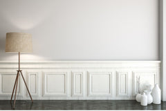 Image of an empty wall.  There is molding on the lower half.  A lamp in front and some ceramic vases.