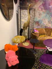 Showroom image of a black table with some felt dogs sitting on it, golden crane behind.