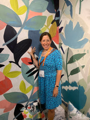 Me standing in front of a wallpaper that has large painted flowers.