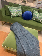 Velvet grass green sofa and ottoman with accent pillows and throw.