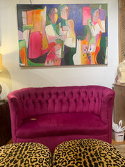 Magenta tufted loveseat with a colorful painting above it and 2 leopard print ottomans below.