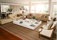 Large living room with a large floor rug under all of the furniture in the room.