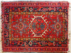 A small persian rug, mostly red with blue accents