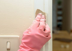 Gloved hand sanding down door trim