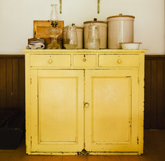 old yellow cabinet with jars on top