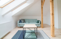 Light blue sofa in a bright open loft area with a slanted ceiling over the sofa.