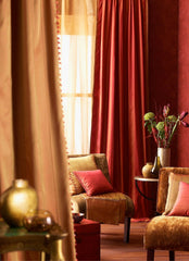 Lush and rich close up of a living room with silk and velvet curtains in beautiful golds and reds.