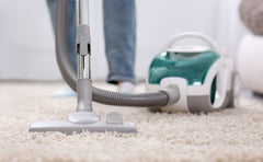 Close up of a vacuum from the floor and a person behind it vacuuming.