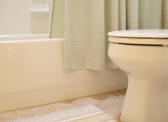 Looking at a close up of a tub, edge of toilet and a rug on the floor.