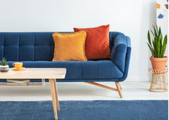 Blue sofa with orange and yellow pillow.