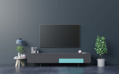 Dark blue wall with a large tv in front of it.  TV is sitting on a tv credenza