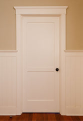 Interior door painted white with white trim and painted wood molding on the lower half of the walls.