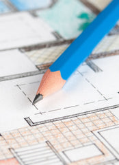 Close up of a colored floor plan with a blue pencil sitting on top.
