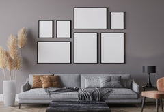 Gray living room wall with a sofa and chair in front, above the sofa are large black framed photos hanging in a gallery style.