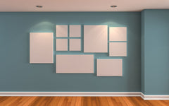 Light blue wall, light wood floor and on the wall is a gallery of white canvases