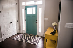 Small foyer area with a teal door, and yellow entry table.