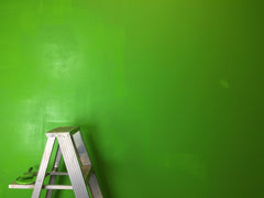 Bright green wall with a metal ladder in the bottom left corner