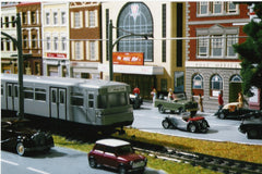 Close up of a model train set up in cityscape.