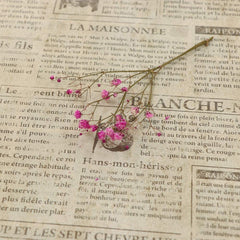 Beige newsprint wallpaper with a sprigg of a pink flower sitting on it.
