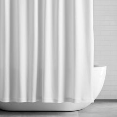 Simple white shower curtain in front of a white tub.