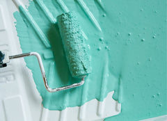 Closeup of paint pan with seafoam green paint and a paint roller.