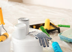 Close up of painter's tools - gloves, paint cans, drop cloths, roller brushes