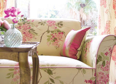 Sofa with a floral pattern in pink, coffee table sitting in front with a crystal vase.
