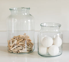 2 glass jars filled with cotton balls and clothes pins