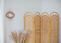 Natural rounded top screen against a white wall with a mirror in the shape of an eye on the wall.