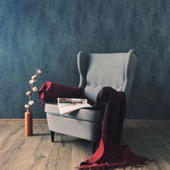 Gray wing back chair with a red throw on it and an open magazine sitting on it.