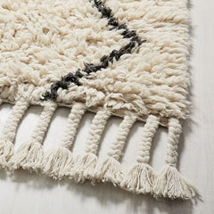 Close up of corner of a thick white wool rug with a black design on it.