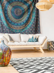 Bohemian looking living room, with a cream sofa.  Large circular tapestry above the sofa.  Wicker hanging lights.
