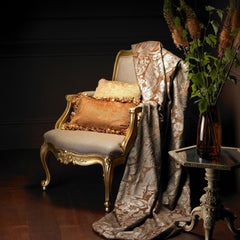 Traditional chair with gold pillows and a damask fabric draped over it.