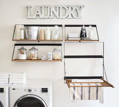 Close up of wall with dryer and shelves above with metal letters Laundry above