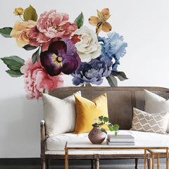 Simple sofa with large flowers on the wall behind it.