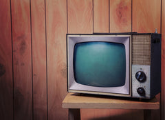 An old tv in front of a wood paneled wall.
