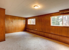 An empty room where all the walls are wood paneling.