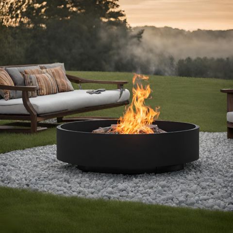 A round black fire pit with a fire sitting on gravel with an outside couch in the background.