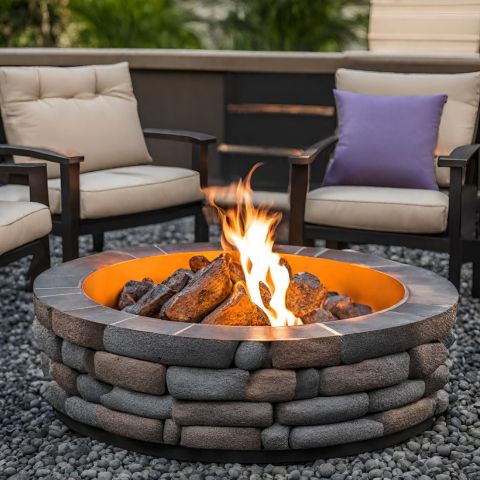 A round fire pit made of stone sitting on rocks with patio furniture.