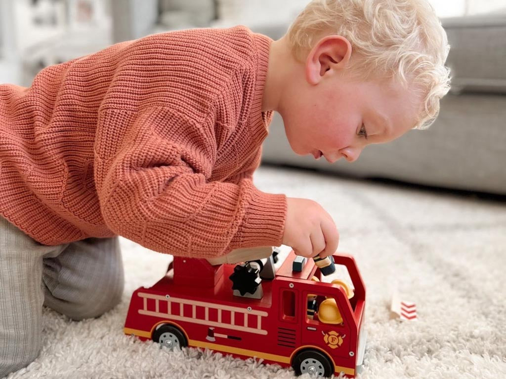 Boy playing independently with a wooden fire engine