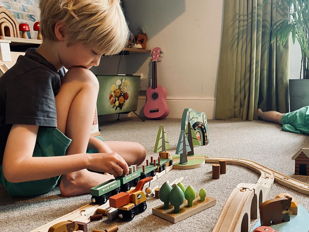 A boy playing with a wooden train set