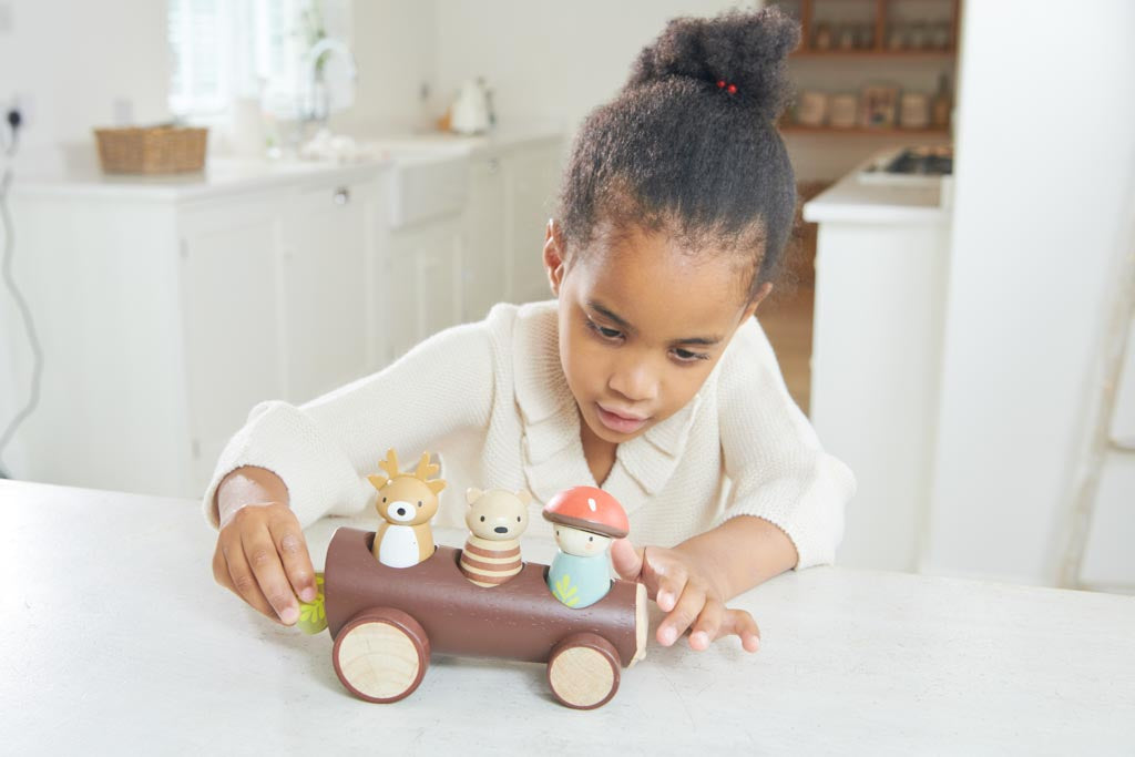 Girl playing with a wooden toy car