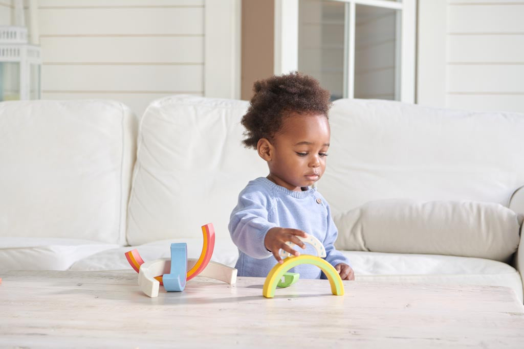 A toddler playing with a rainbow stacking toy