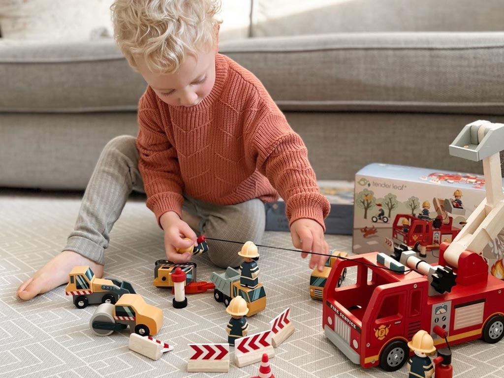 A boy playing with a toy fire engine