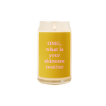 A 16 oz. candle with a yellow decal on it with the phrase "OMG, what is your skincare routine" printed on.