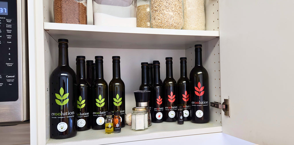 Evoolution olive oils and vinegars are stored in a kitchen cupboard along with salts, sugar and other pantry items.