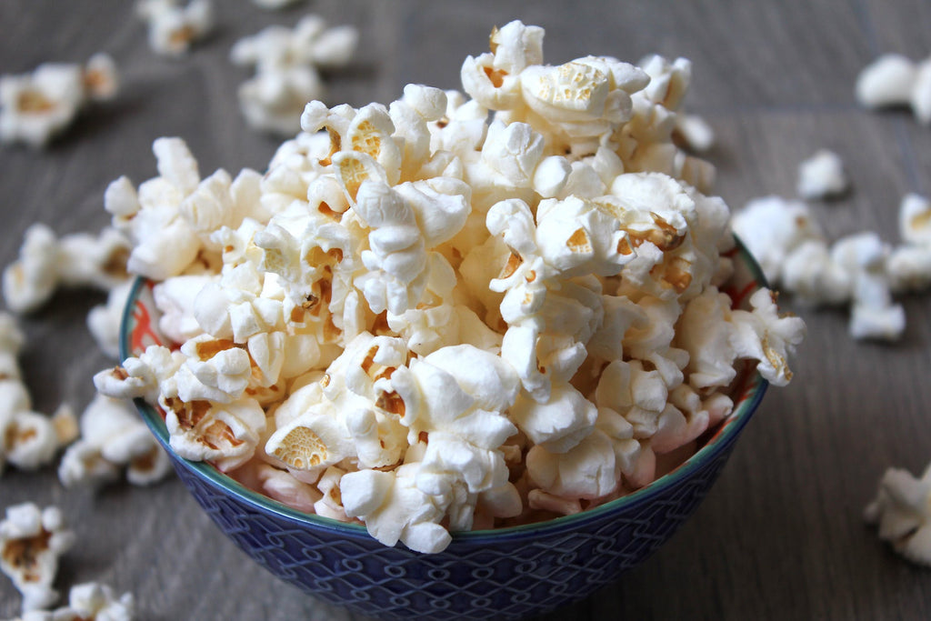An overflowing blue bowl of popcorn sits atop a table