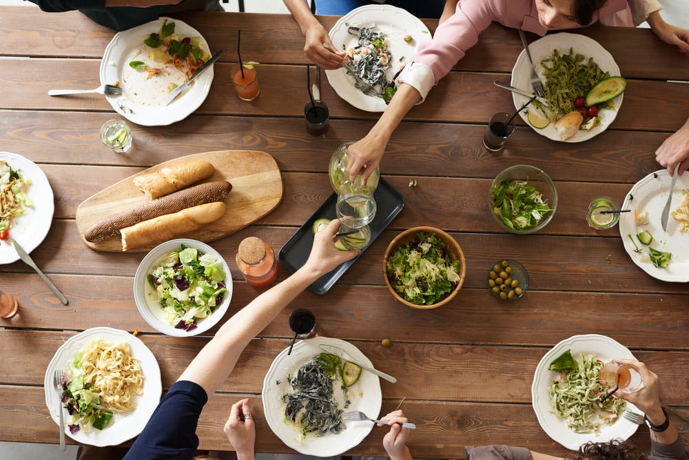 A group of people share a fresh, healthy meal at a large wooden table