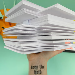a pile of cards made from FSC accredited cardstock being held up by a hand with a tattoo that says keep the heid